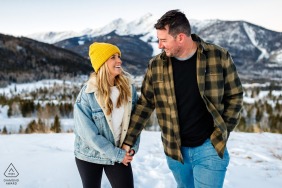An after the wedding proposal engagement picture session in Frisco, Colorado as the couple walks holding hands in the winter snow
