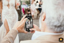 A beautiful shot capturing a guest taking a mobile phone picture of the elegant bride on her wedding day at Borgo Fregnano in Faenza, Italy.